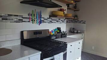 A kitchen with a black range hood, white cabinets, and a tiled backsplash.