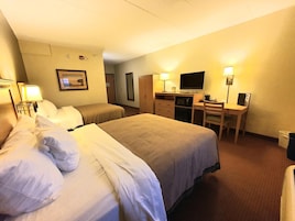 Habitación de hotel con dos camas, un escritorio, un televisor y un espejo.