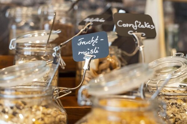 Exhibición de alimentos en frascos de vidrio con etiquetas que indican 'Frucht-Musli' y 'Cornflakes'.