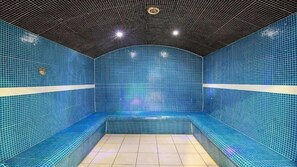 Een sauna met blauwe tegels, banken en een betegelde vloer.