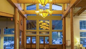 Eine großzügige Lobby mit hoher Decke, großen Fenstern und einem zentralen Kronleuchter.