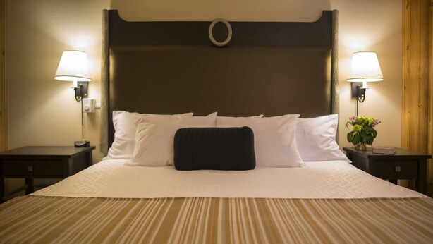 Ein Hotelzimmer mit einem großen Bett, zwei Nachttischen und zwei Wandlampen.