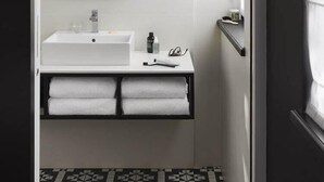 A bathroom with a white sink, a mirror, and a black and white patterned floor. - Hotel Louvre Lens (Lens)