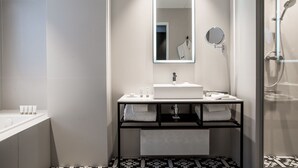 A modern bathroom with a large mirror, a white sink, and a shower area. - Hotel Louvre Lens (Lens)