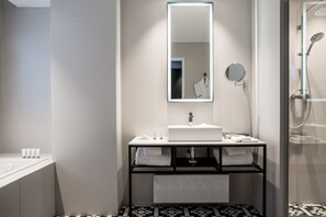 A modern bathroom with a large mirror, a white sink, and a shower area. - Hotel Louvre Lens (Lens)