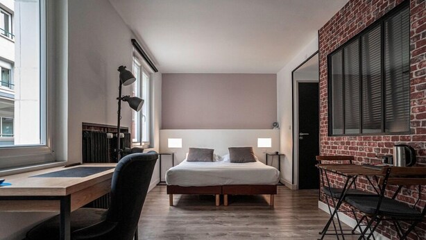A modern bedroom with a large bed, a desk, and a dining area. - Alive Hotel de Quebec (Rouen)