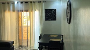 Un espace repas comprenant une table et des chaises, un élément de décoration murale circulaire de couleur noire et un canapé noir.