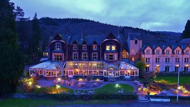 Un gran hotel de varios pisos con una destacada estructura de cristal y un espacio al aire libre con mesas.