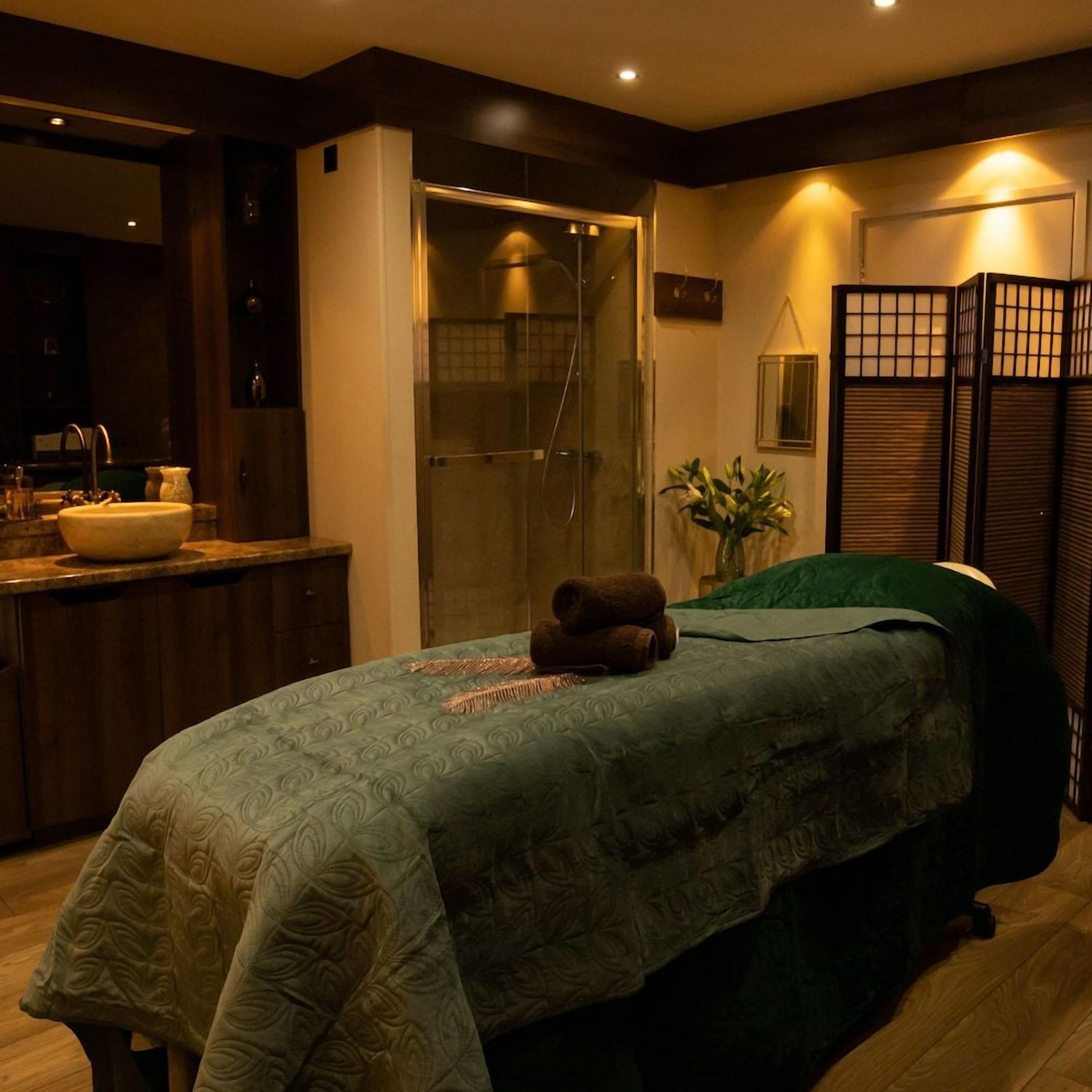 A hotel room with a bed, a bathroom, and a small sitting area.