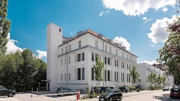 Ein weißes Gebäude mit vielen Fenstern und einem roten Hydranten am Bürgersteig.
