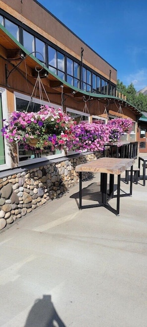 A building with a stone wall, hanging flower baskets, and outdoor tables.
