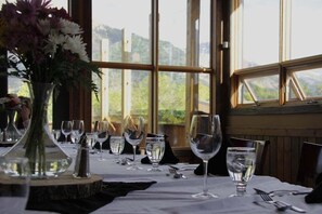 A dining table set with wine glasses, water glasses, and cutlery, with a vase of flowers on the table.