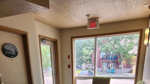 A hallway with a door, two armchairs, a large window, and a ceiling-mounted exit sign. - Waterton Lakes Lodge Resort (Waterton Park)
