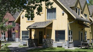 A yellow building with a stone foundation, large windows, and a covered porch. - Waterton Lakes Lodge Resort (Waterton Park)