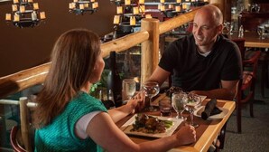 A couple dining in a restaurant with wooden furniture and candle-lit chandeliers. - Waterton Lakes Lodge Resort (Waterton Park)