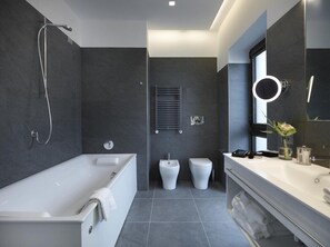 A modern bathroom with a bathtub, two toilets, a vanity with a mirror, and a shower. - Boutique Hotel Touring (Verona)