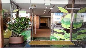 Ein Hotel Eingang mit einem Blumentopf, einer Fußmatte und Glastüren.