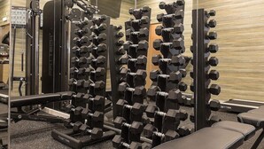 Ein Fitnessstudio mit mehreren Hantelständern und Trainingsgeräten.