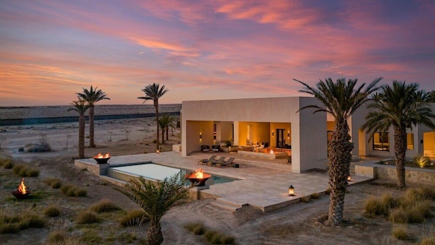 Un resort moderno con piscina, asientos al aire libre y palmeras.