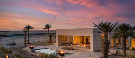 A modern resort with a pool, outdoor seating, and palm trees.