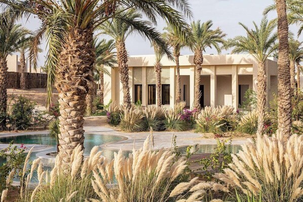 Un resort con piscina, palmeras y un edificio de columnas.