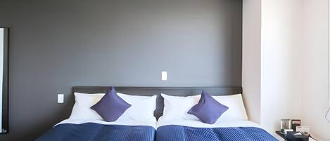 A double bed with a dark headboard, two white pillows, and two dark pillows.