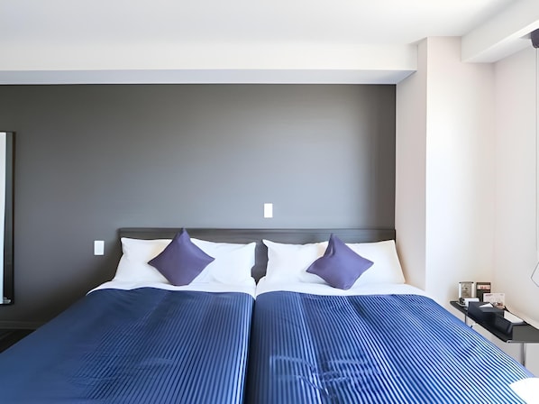 A double bed with a dark headboard, two white pillows, and two dark pillows. - Hotel Livemax Takadanobaba Ekimae (Tokyo)