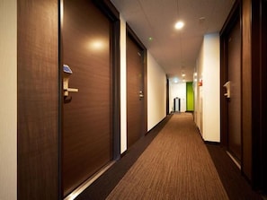 A hotel corridor with wooden doors, carpeted floors, and a green wall at the end. - Super Hotel Shinjuku Kabukicho (Tokyo)