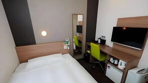Ein Hotelzimmer mit Bett, Schreibtisch mit Stuhl, Fernseher und einer kleinen Küchenzeile.