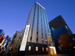 Um hotel alto com uma placa que diz 'SuperHotel' e um estilo arquitetônico moderno.