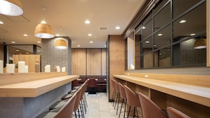 Een moderne bar met houten toonbanken, comfortabele barstoelen en hanglampen.
