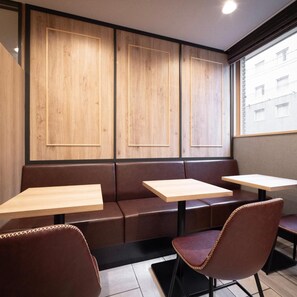 Eine Sitzecke mit Holzwandverkleidung, Ledersitzbänken und Holztischen.