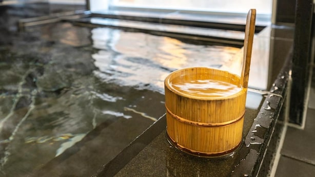 Een warmwaterbron met een houten bak en een opscheplepel op een platform.