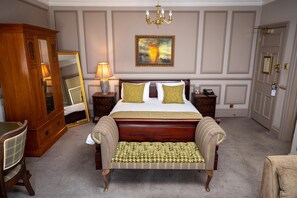 A bedroom with a large bed, a wooden wardrobe, a bench, a bedside table with a lamp, and a painting on the wall. - Cedars Lodge Inn (Barnstaple)