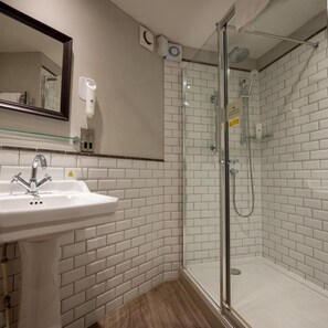A bathroom with a white sink, a glass shower enclosure, and a mirror. - Cedars Lodge Inn (Barnstaple)