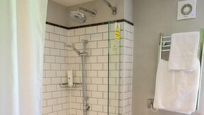 A bathroom with a glass-enclosed shower, a white bathtub, and a towel rack. - Cedars Lodge Inn (Barnstaple)
