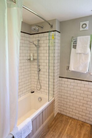 A bathroom with a glass-enclosed shower, a white bathtub, and a towel rack. - Cedars Lodge INN (Barnstaple)
