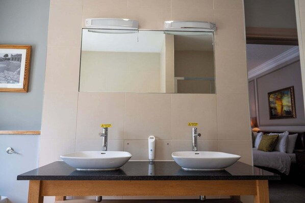 A bathroom with two sinks, a mirror, and a towel dispenser. - Cedars Lodge INN (Barnstaple)