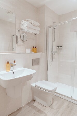 A modern bathroom with a sink, toilet, and glass shower enclosure. - Cabarfeidh Hotel (Stornoway)