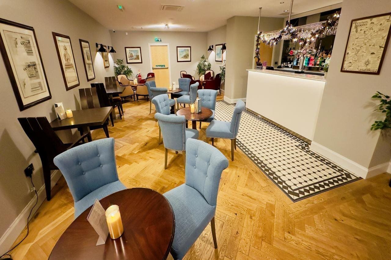 En hotellobby med en bardel, sittgrupper och inramade tavlor på väggarna.