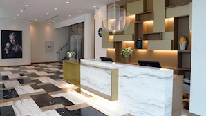 A modern reception area with a marble reception desk, geometric patterned floor, and contemporary shelving with decorative items. - Galata's Hotel Istanbul (Istanbul)