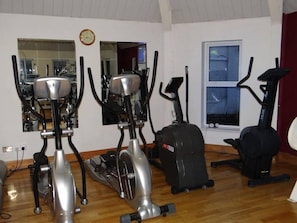 Una palestra in casa con cyclette, ellittica e tapis roulant.