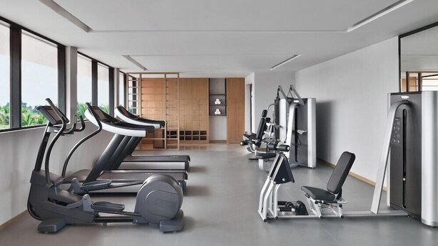 Une salle de sport moderne équipée de tapis de course, de vélos elliptiques et de matériel de musculation.