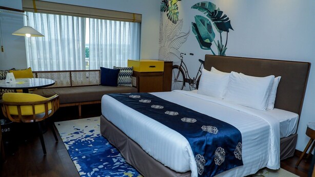 Une chambre d’hôtel avec un lit, un canapé, une table à manger et un vélo.
