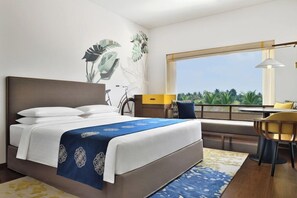 Een moderne hotelkamer met een groot bed, een bureau en uitzicht op groen.