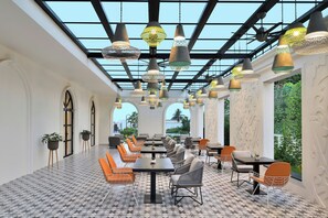 Un espace intérieur spacieux, doté de nombreuses tables et chaises, d’un sol à motifs et de luminaires suspendus.