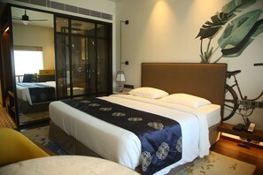 Een hotelkamer met een groot bed, een fiets en een spiegel.