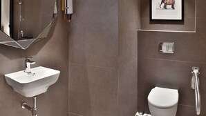 Une salle de bain moderne avec un grand miroir, un lavabo, des toilettes et une douche.