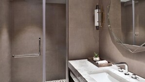 Une salle de bain moderne avec une douche à parois de verre, un lavabo en marbre et un grand miroir.