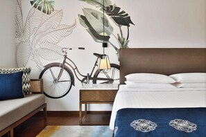 Een slaapkamer met een groot bed, een houten nachtkastje, een fiets en een muurschildering.